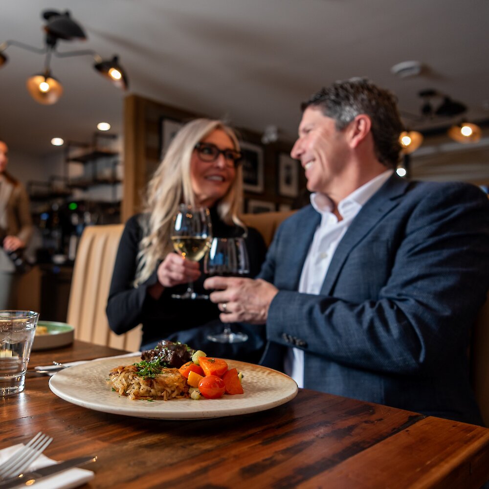 A couple cheers their wine glasses dining at Isagani Farm-to-Table in Kamloops, BC.