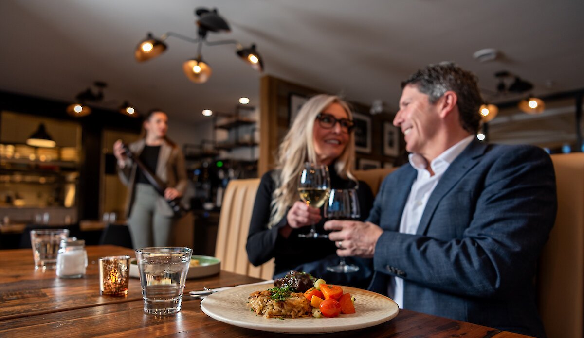 A couple cheers their wine glasses dining at Isagani Farm-to-Table in Kamloops, BC.