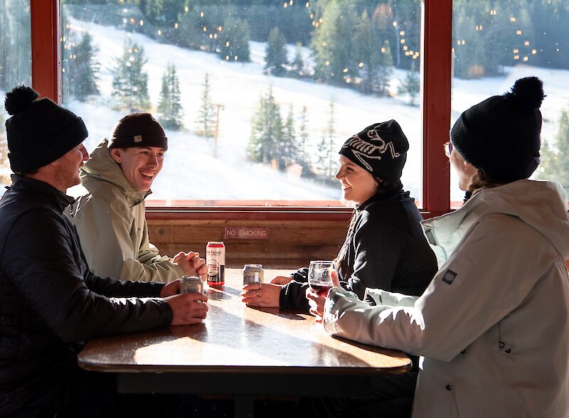 A group of friends enjoying a beer in the cozy Harper Mountain Lodge near Kamloops, BC.