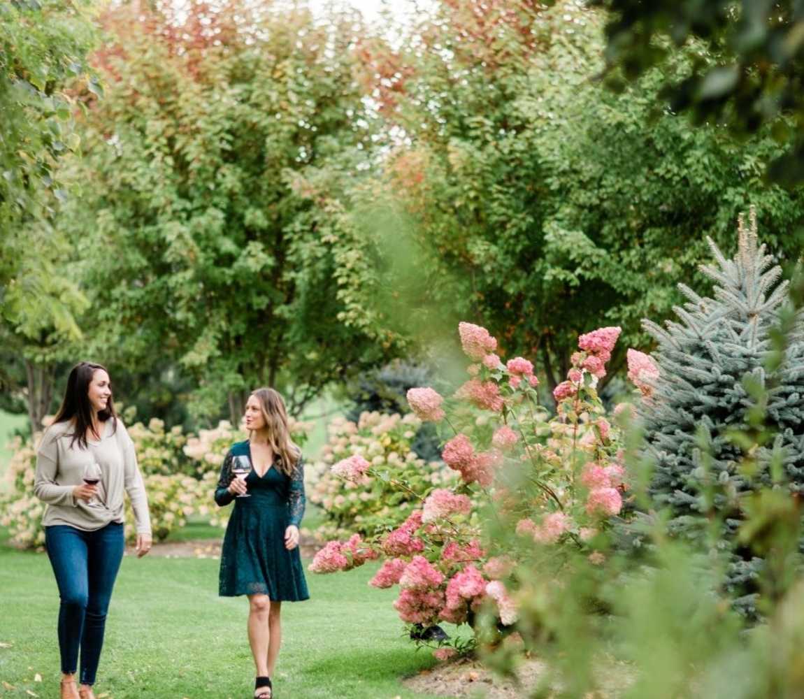 Two individuals walking through the gardens with a glass of wine at Privato Vineyard + Winery