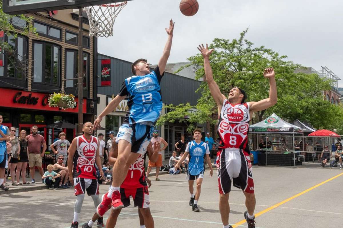 three players playing basketball on the streets in downtown kamloops