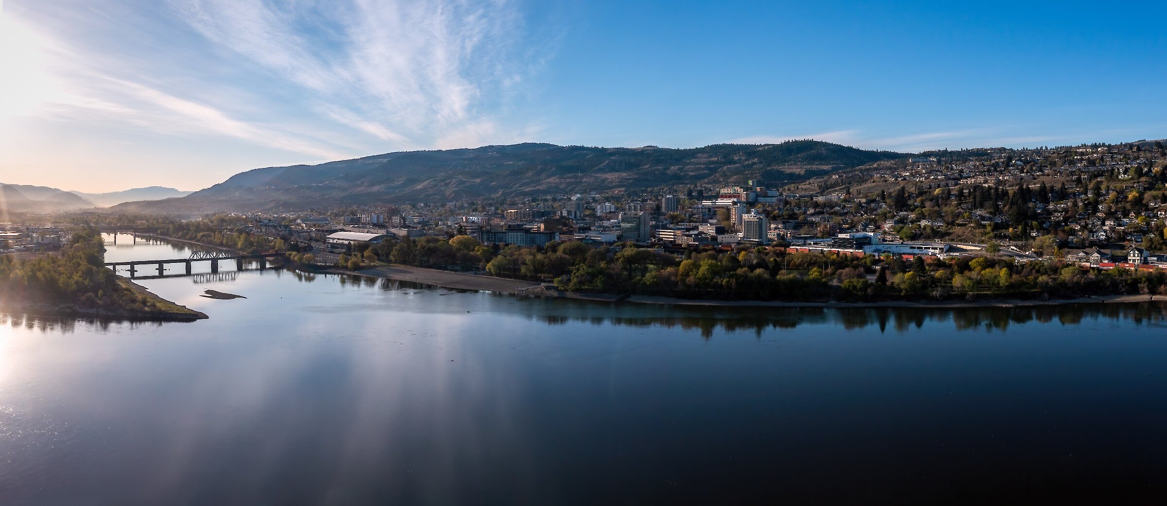 The Thompson River and city of Kamloops BC on a sunny day with a few clouds in the sky.