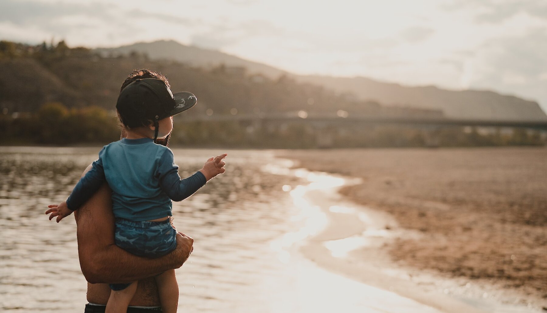 A father holding his son on a summer day at Overlander Beach located on the the North Shore in Kamloops British Columbia.