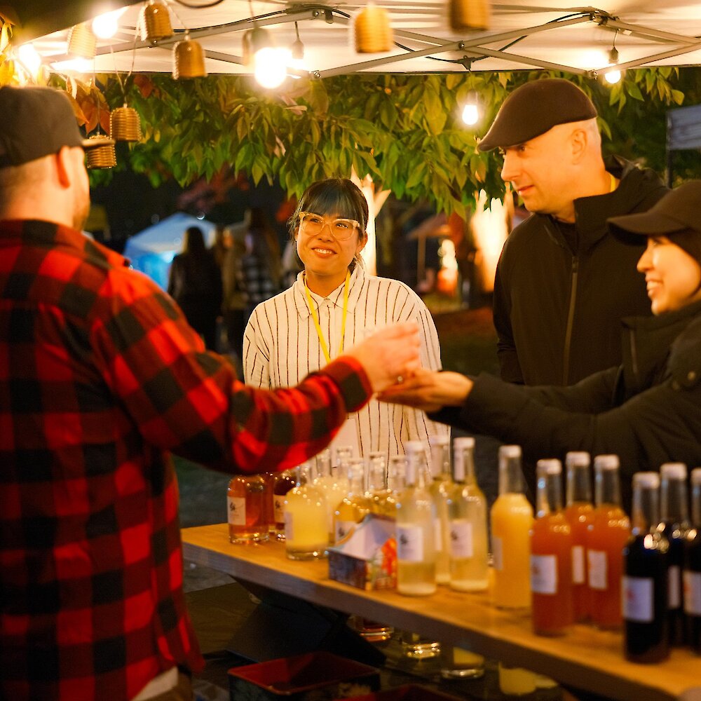 Drink provider hands a festival goer their beverage at one of the Brewloops drinks booth.