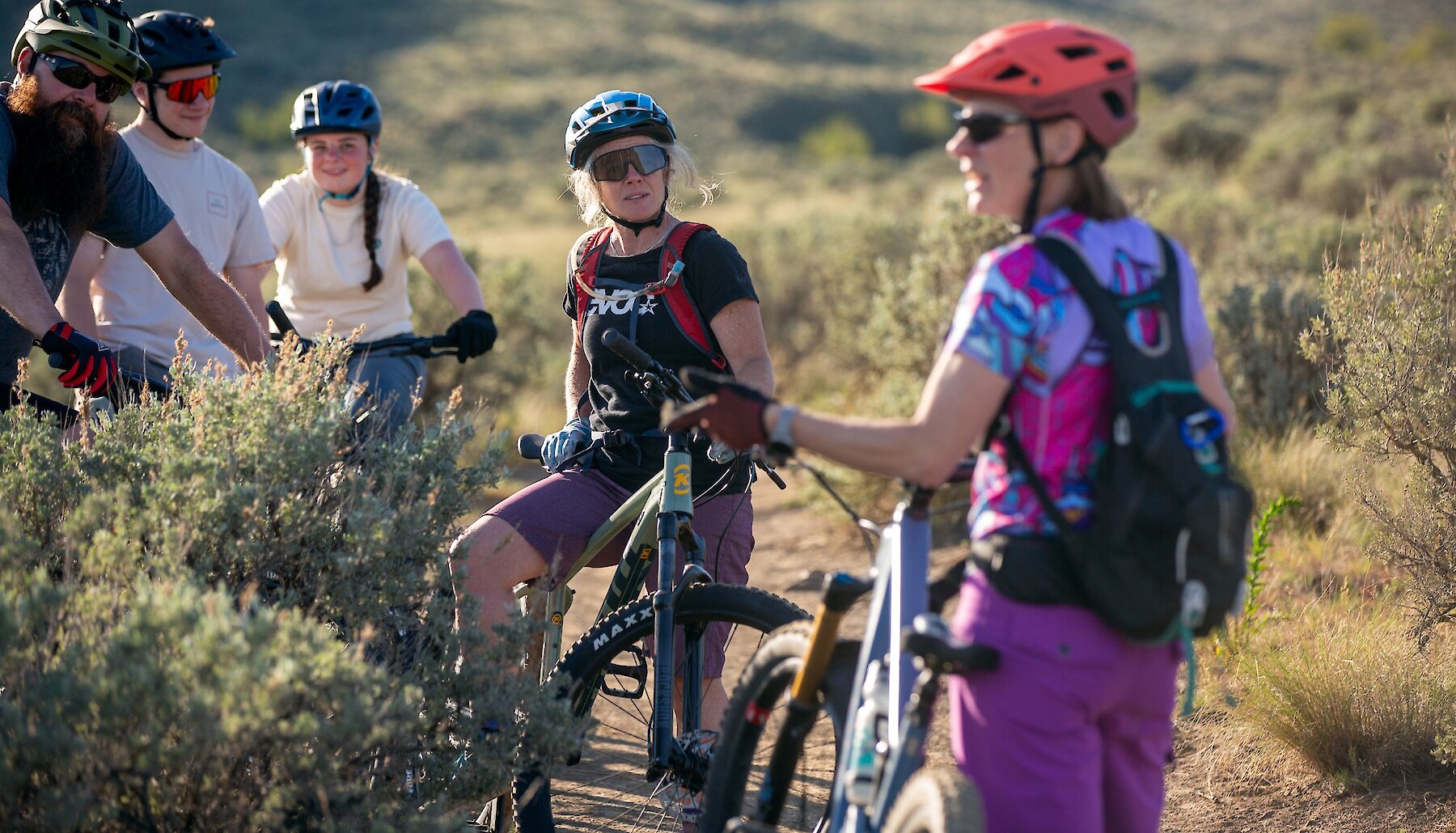 Group of visitors riding their ebikes along Riverside trail in Kamloops with the Thompson River and mountains in the background.