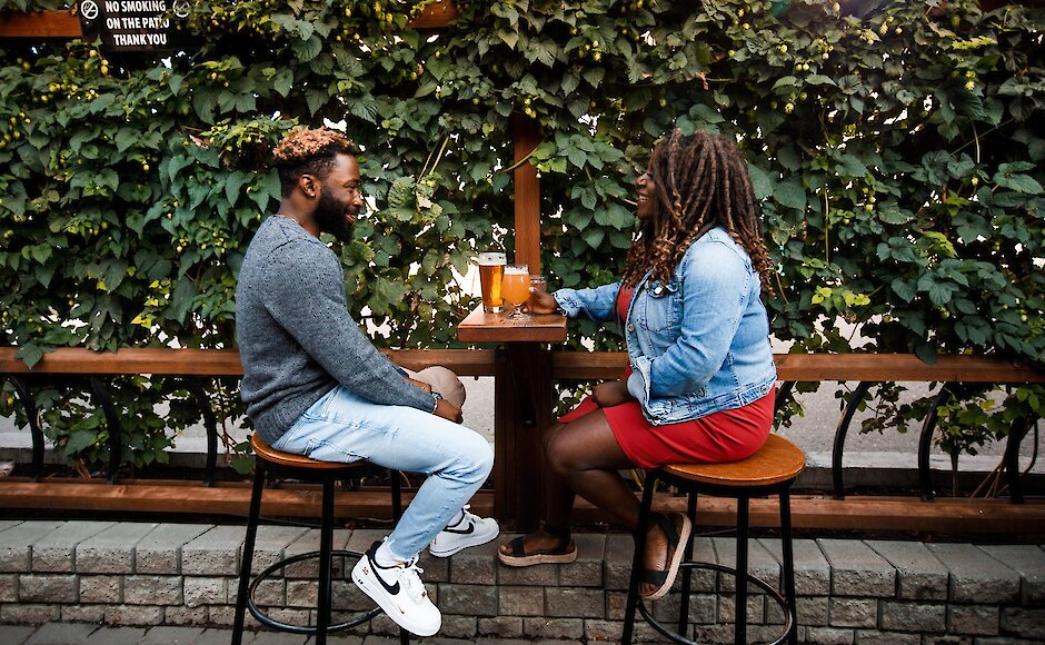 A couple relaxing on a sunny patio lined with hops at Red Collar Brewing in Kamloops, British Columbia.