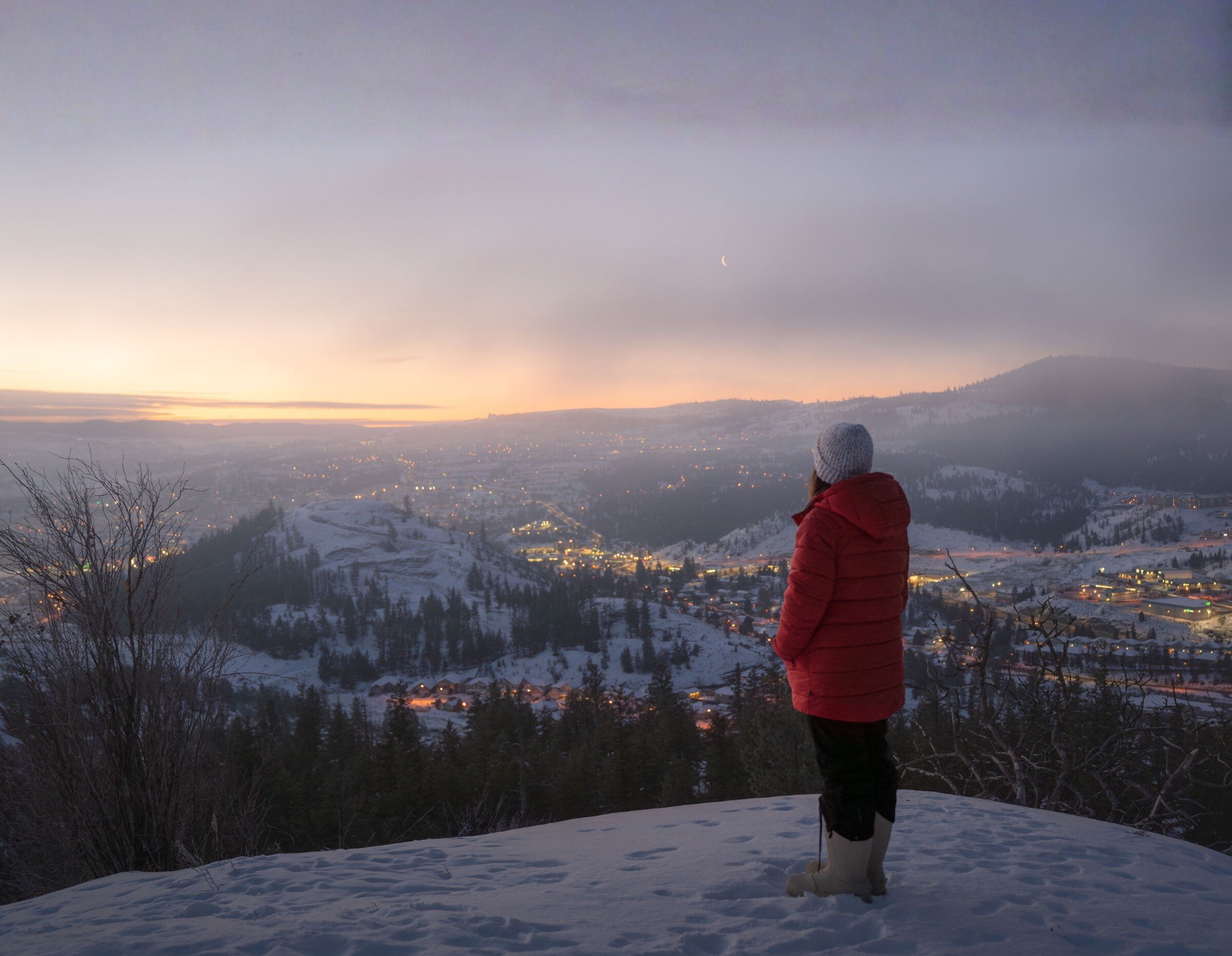 A woman enjoys fresh snowfall at dusk in Kamloops, BC
