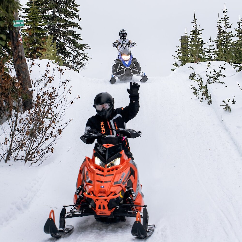 Two snowmobilers coming down the snowy trail near Kamloops, BC.