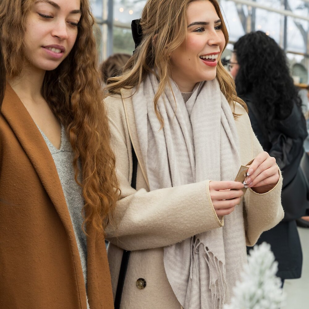 A couple cheers-ing their glasses of red wine in the Privato Vineyard and Winery tasting room with a Christmas tree, wine barrels, and holiday decor in the background.