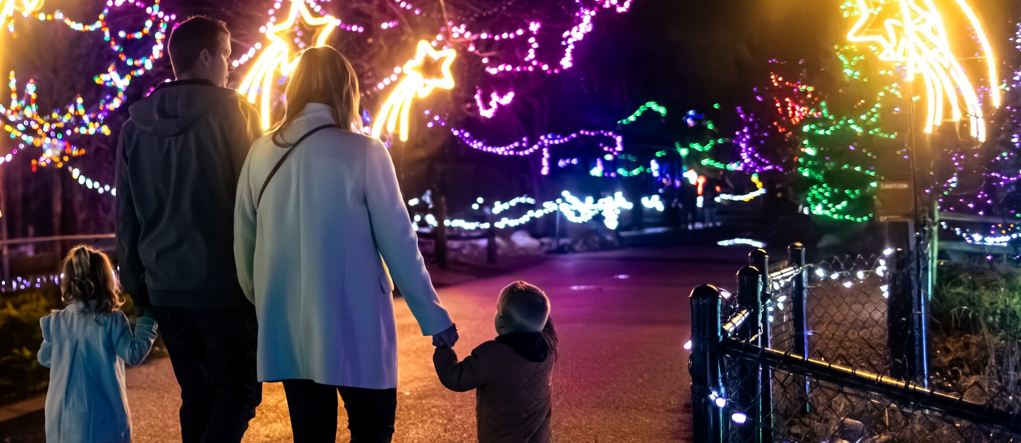 A family walking through the glowing Christmas light display at Wildlights at the BC Wildlife Park in Kamloops.