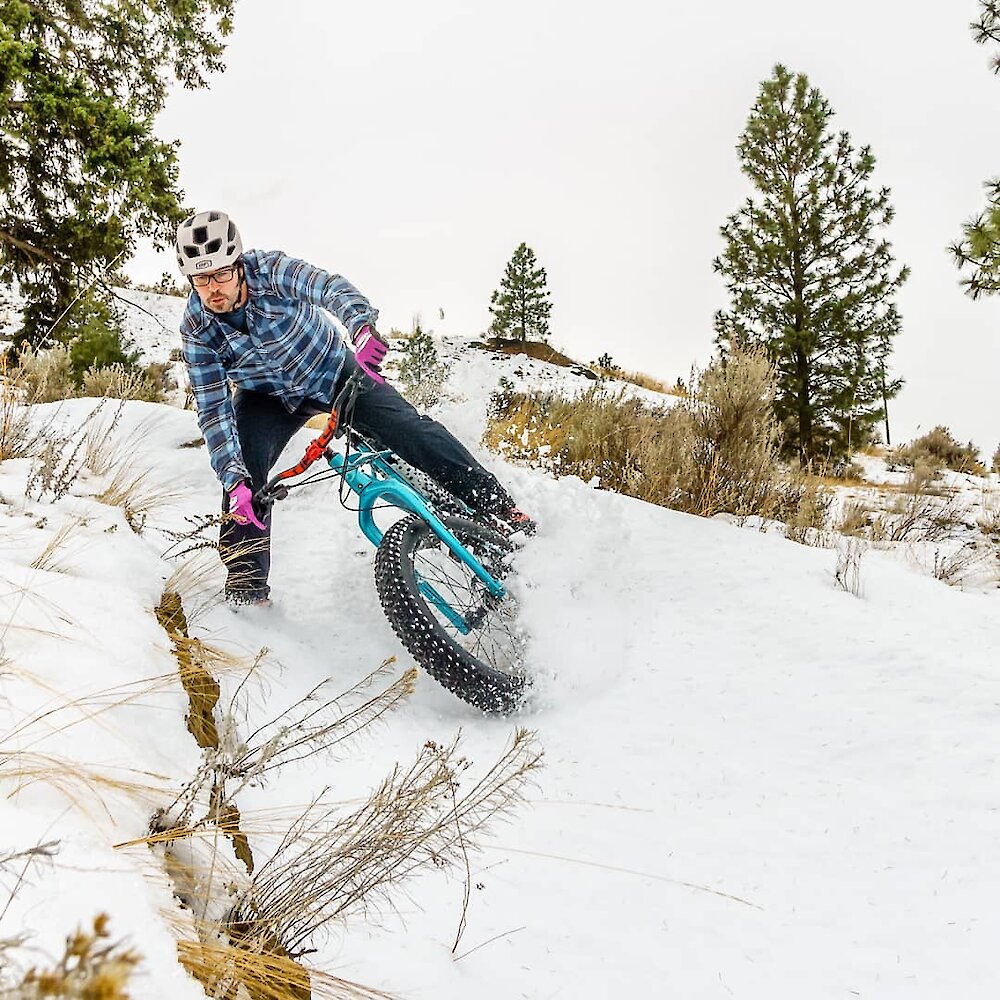 A man rides a mountain bike down a snowy trail near Kamloops BC.