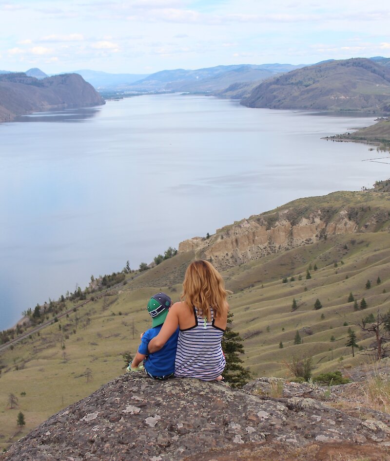 A Mother and son admiring the view over Kamloops Lake from a hiking viewpoint in Kamloops, BC.