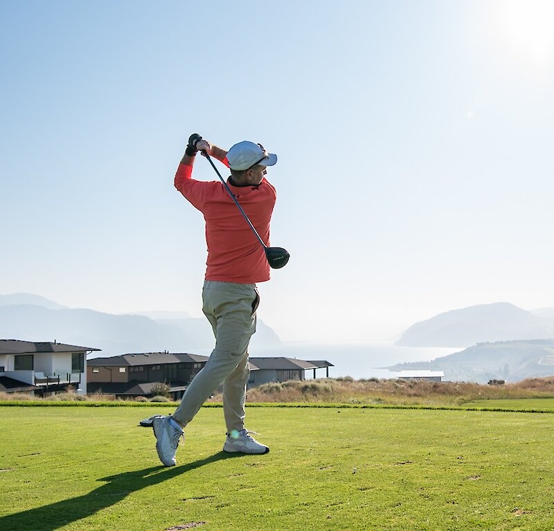 Golfer swinging his club on a sunny day at Tobiano golf course located in Kamloops, BC.