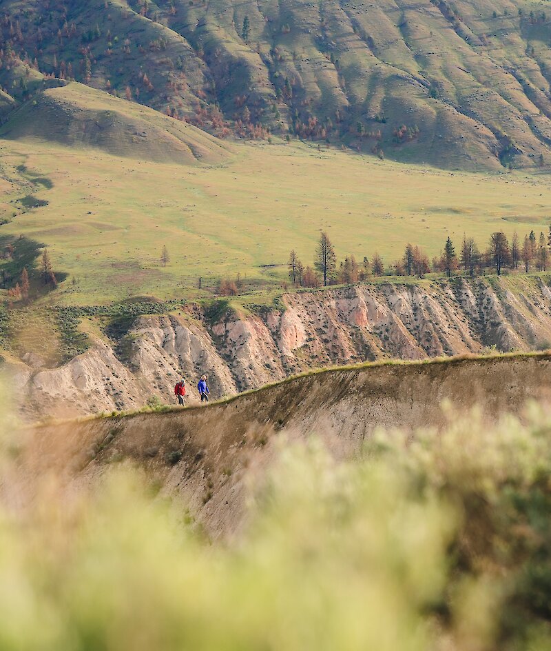 Two hikers walking along the ridge in Valleyview Nature Park with the silt bluffs in the background.