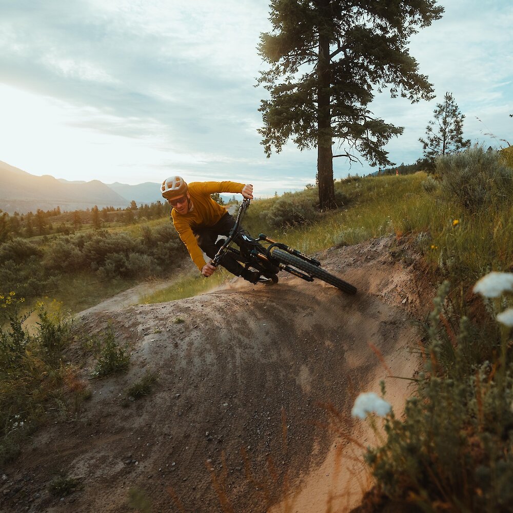 Pro mountain biker Matt Hunter riding a trail at the Kamloops Bike Ranch surrounded by flowers and greenery in Kamloops, BC.