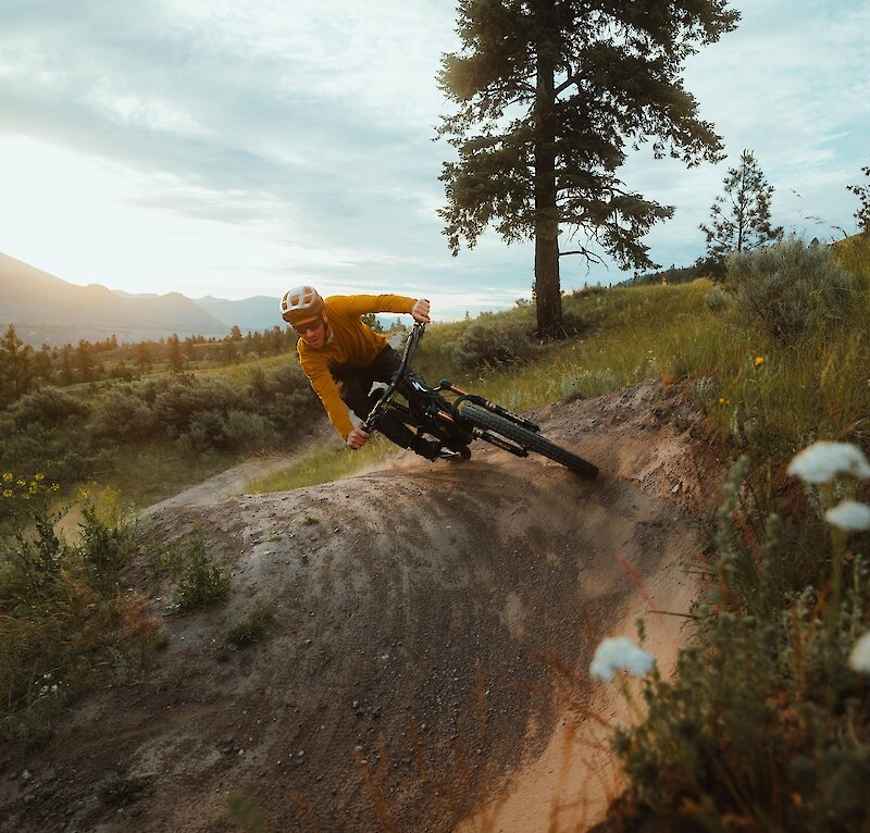 Pro mountain biker Matt Hunter riding a trail at the Kamloops Bike Ranch surrounded by flowers and greenery in Kamloops, BC.