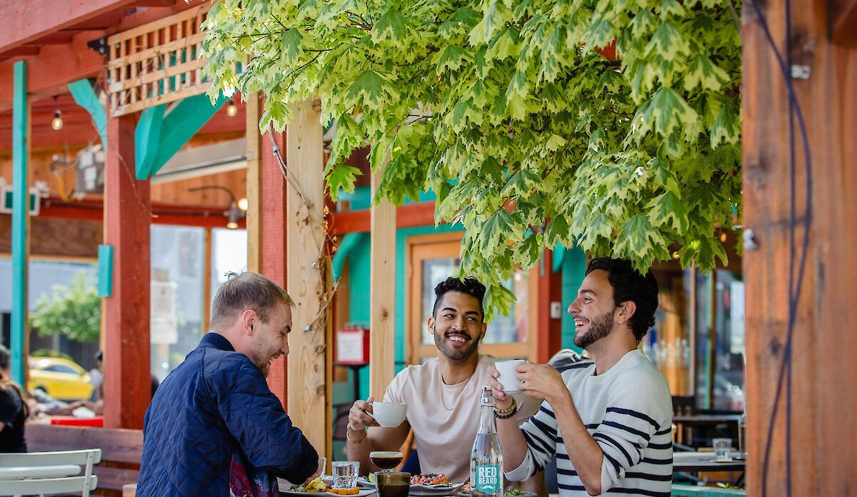 Three people eating at an outdoor patio restaurant table in Kamloops.