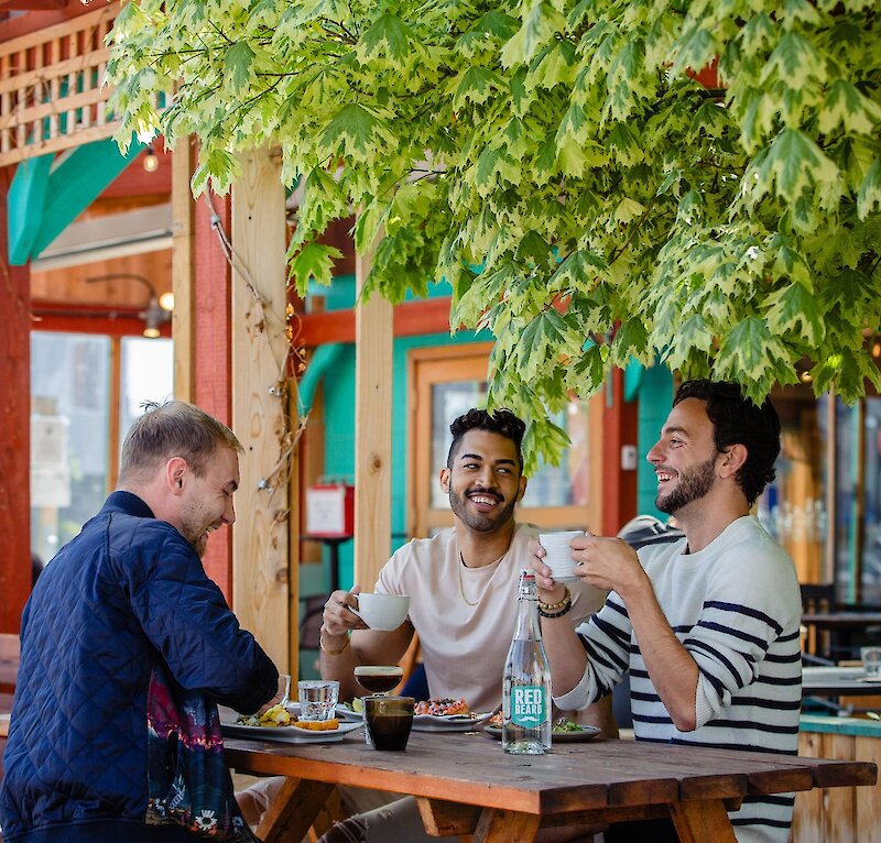 Three people eating at an outdoor patio restaurant table in Kamloops.