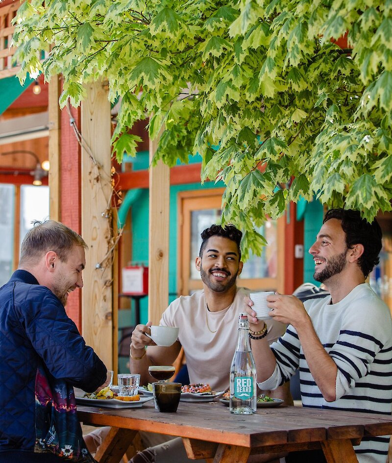 Three people eating at an outdoor patio restaurant table in Kamloops.