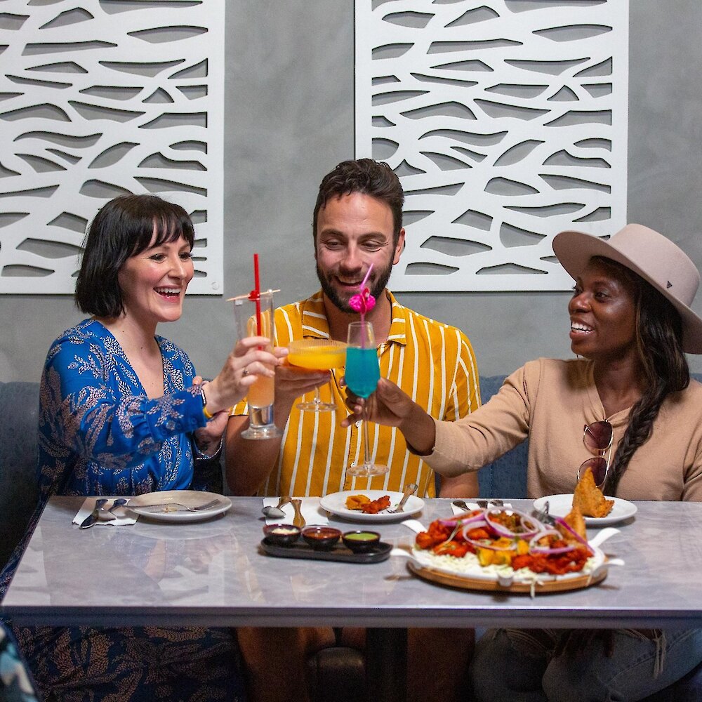 A group cheers their cocktails dining at Maaza Indian Kitchen + Bar in Kamloops, BC.