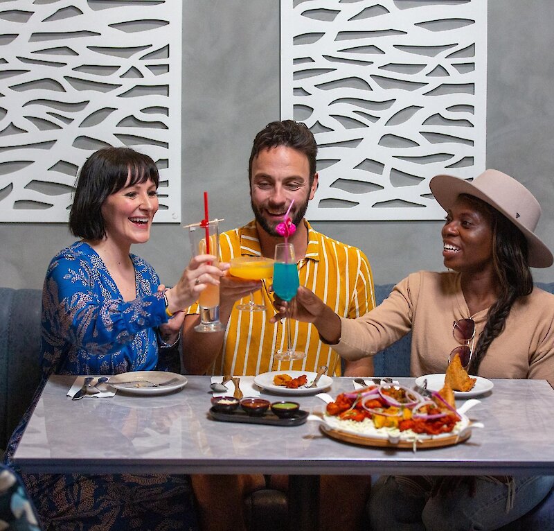 A group cheers their cocktails dining at Maaza Indian Kitchen + Bar in Kamloops, BC.