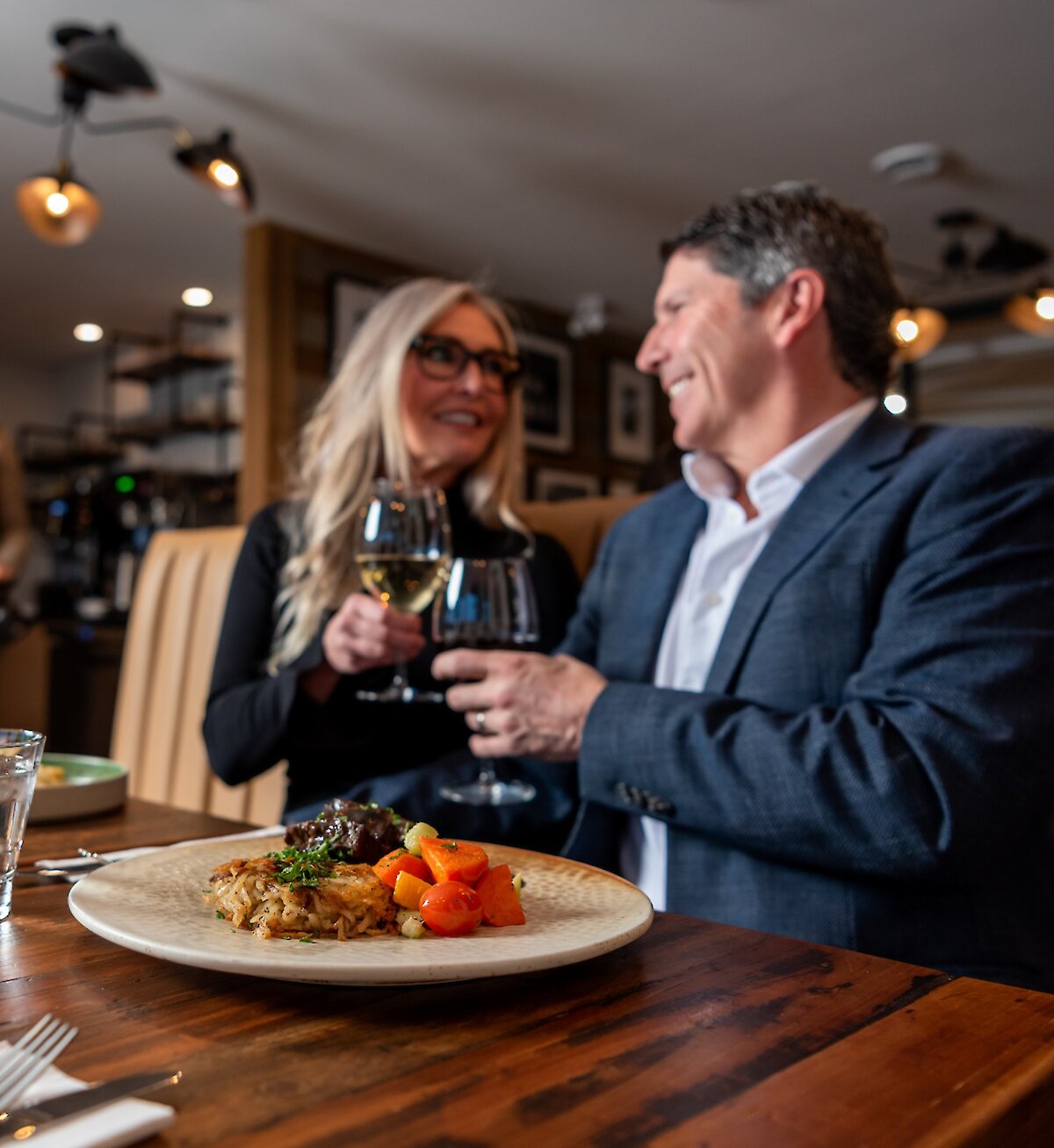 A couple cheers their wine glasses dining at Isagani Farm-to-Table in Kamloops, BC.