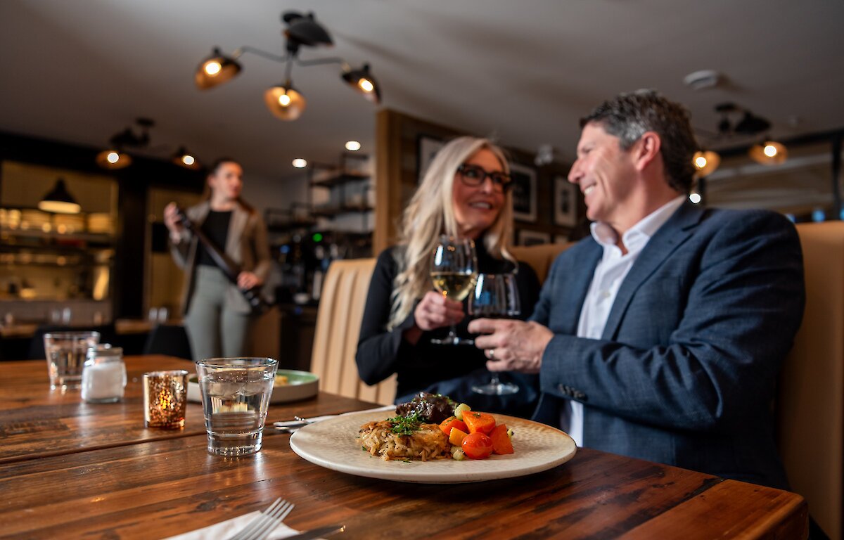 A couple cheers their wine glasses dining at Isagani Farm-to-Table in Kamloops, BC.