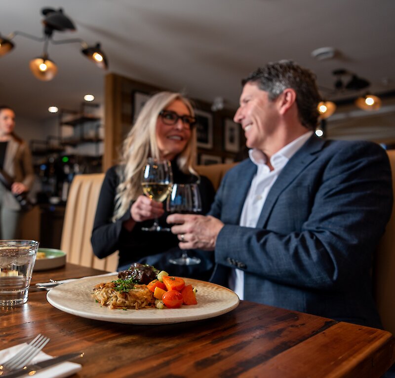 A couple cheers their wine glasses dining at Isagani Farm-to-Table in Kamloops, BC.