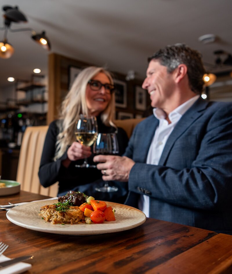 A couple cheers their wine glasses dining at Isagani Farm-to-Table in Kamloops, BC.