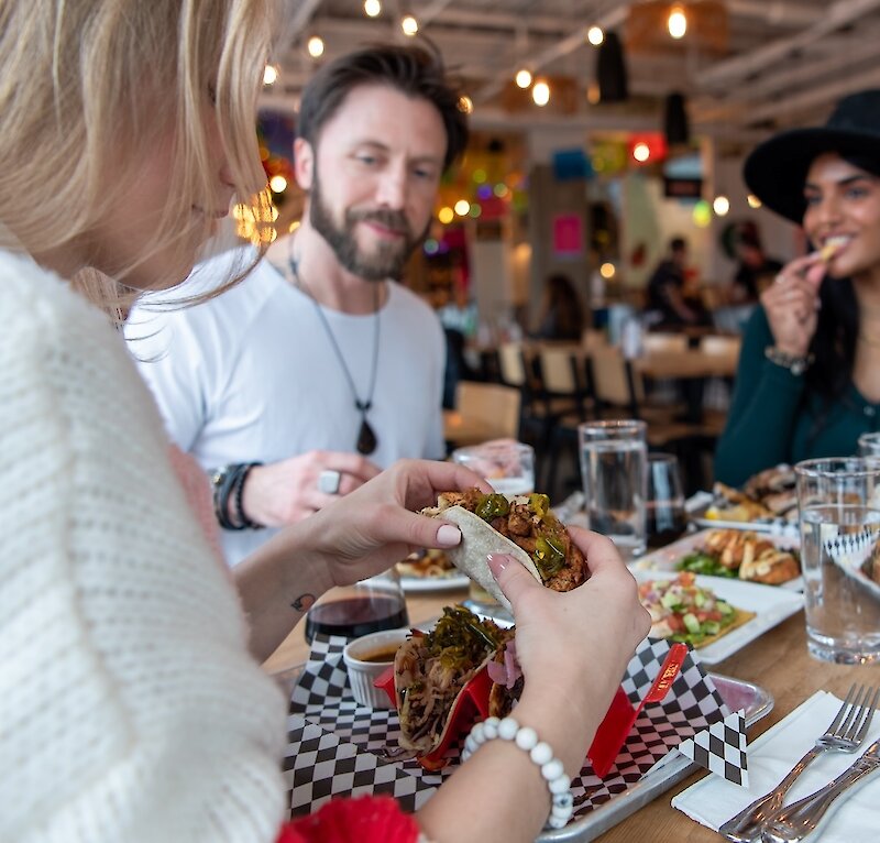 A group of friends eating at Yew Street Food Hall on the North Shore in Kamloops, BC.