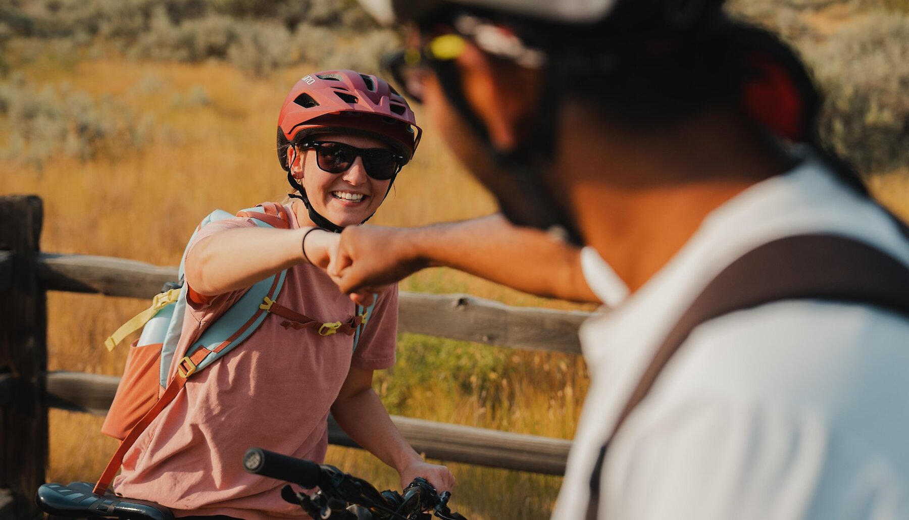 Two riders fist-bump while pausing on their bikes near Kamloops BC