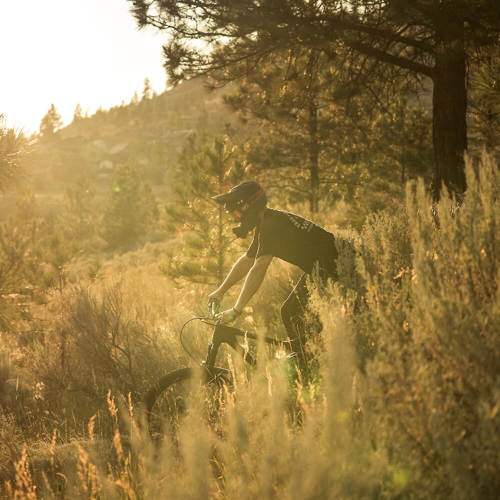 A mountain bike rider navigates the sagebrush on a trail at sunset near Kamloops BC.
