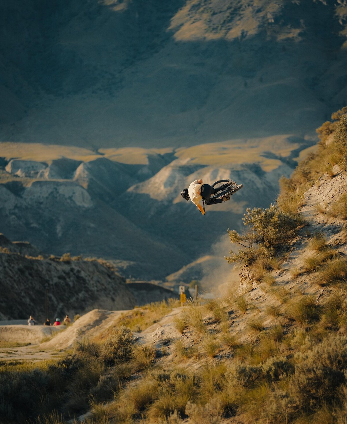 Mountain Biker getting air at the Kamloops Bike Ranch with the mountains in the background.