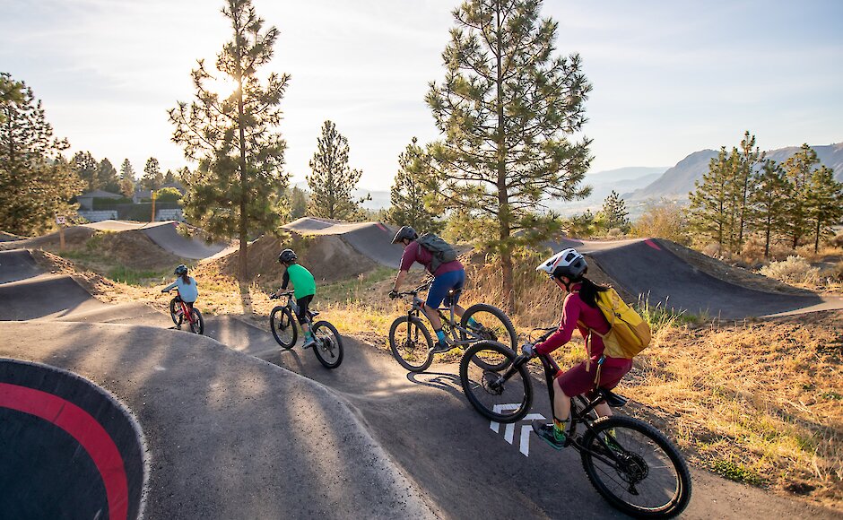 A family rides a pump track at the Bike Ranch in Kamloops, BC