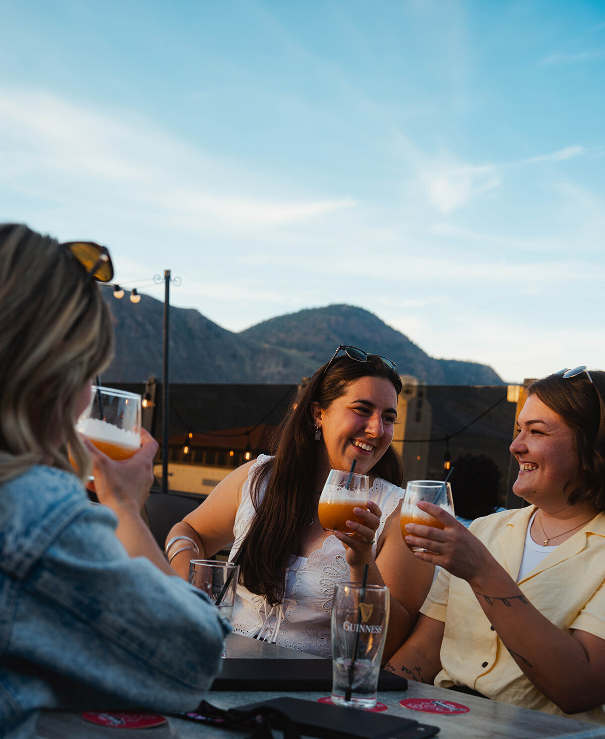 A woman smiling with her glass of wine on the patio at Privato Vineyard and Winery in Kamloops.