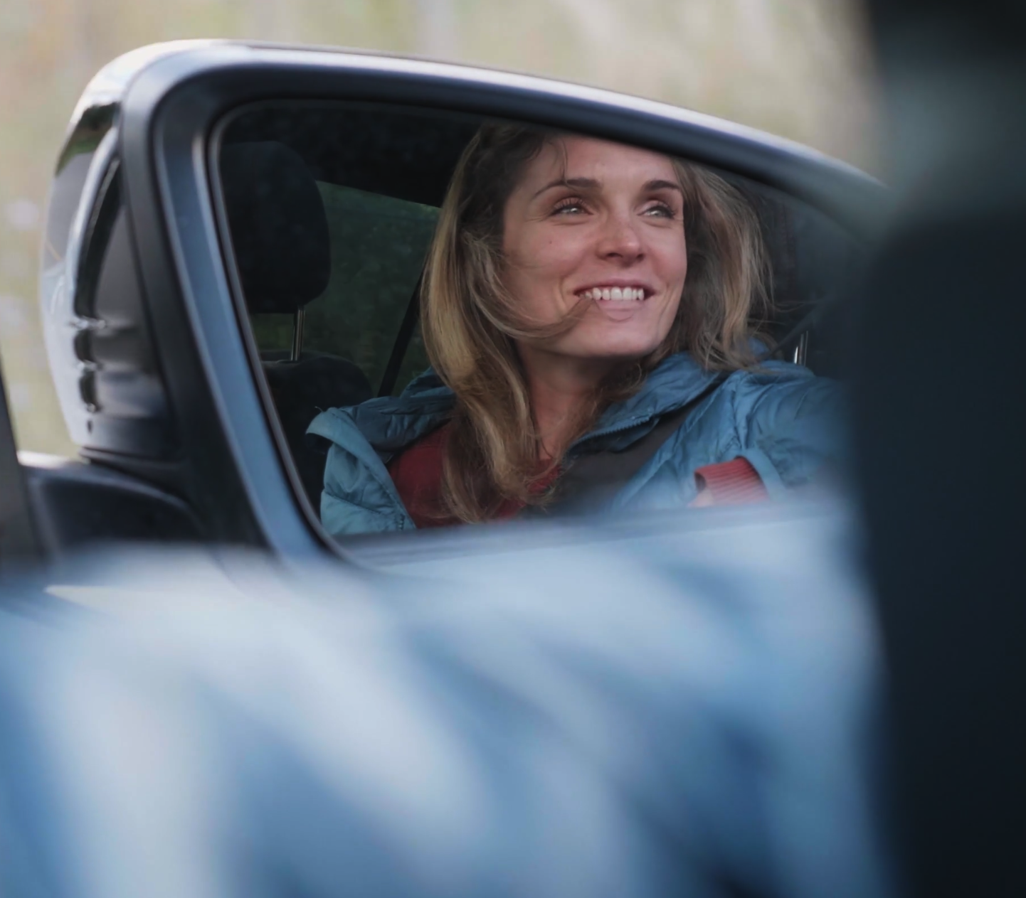 A woman's reflection in a car mirror.