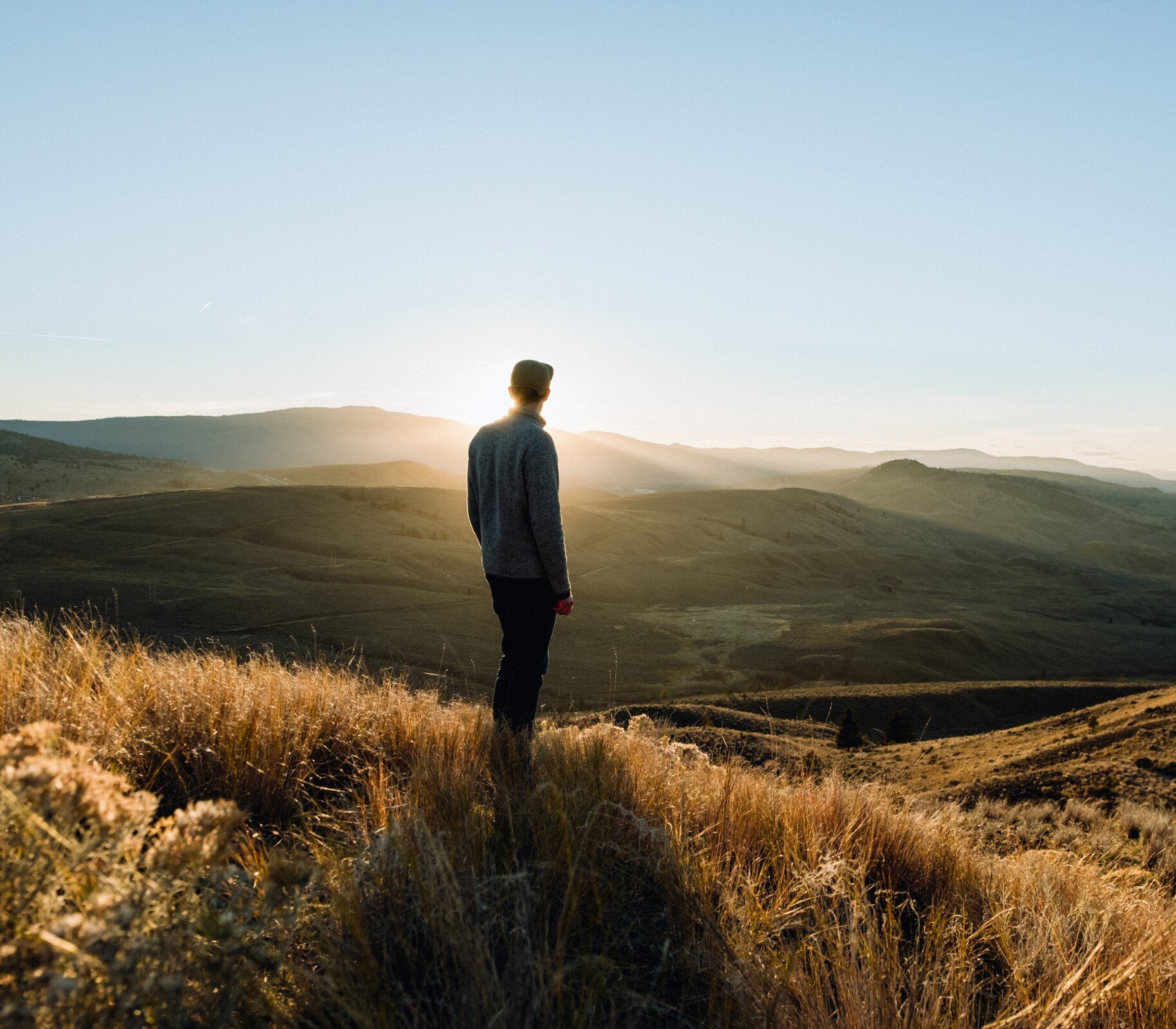 Hiker standing the grasslands of Kenna Cartwright Park admiring the view over the Thompson Valley in British Columbia.