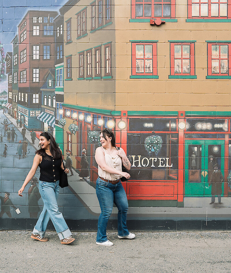 A group of visitors walks along the mural looking up at the artwork in downtown Kamloops,BC.