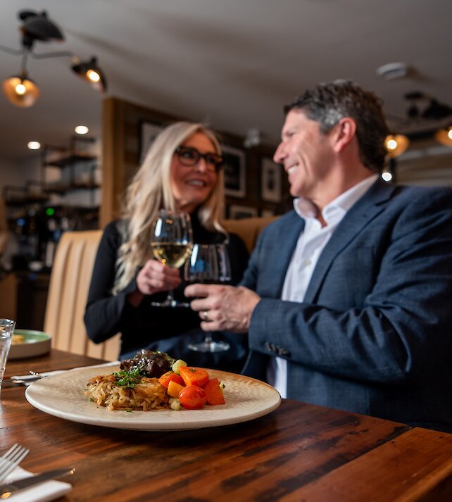 A couple cheers their wine glasses dining at Isagani Farm-to-Table in Kamloops, BC.
